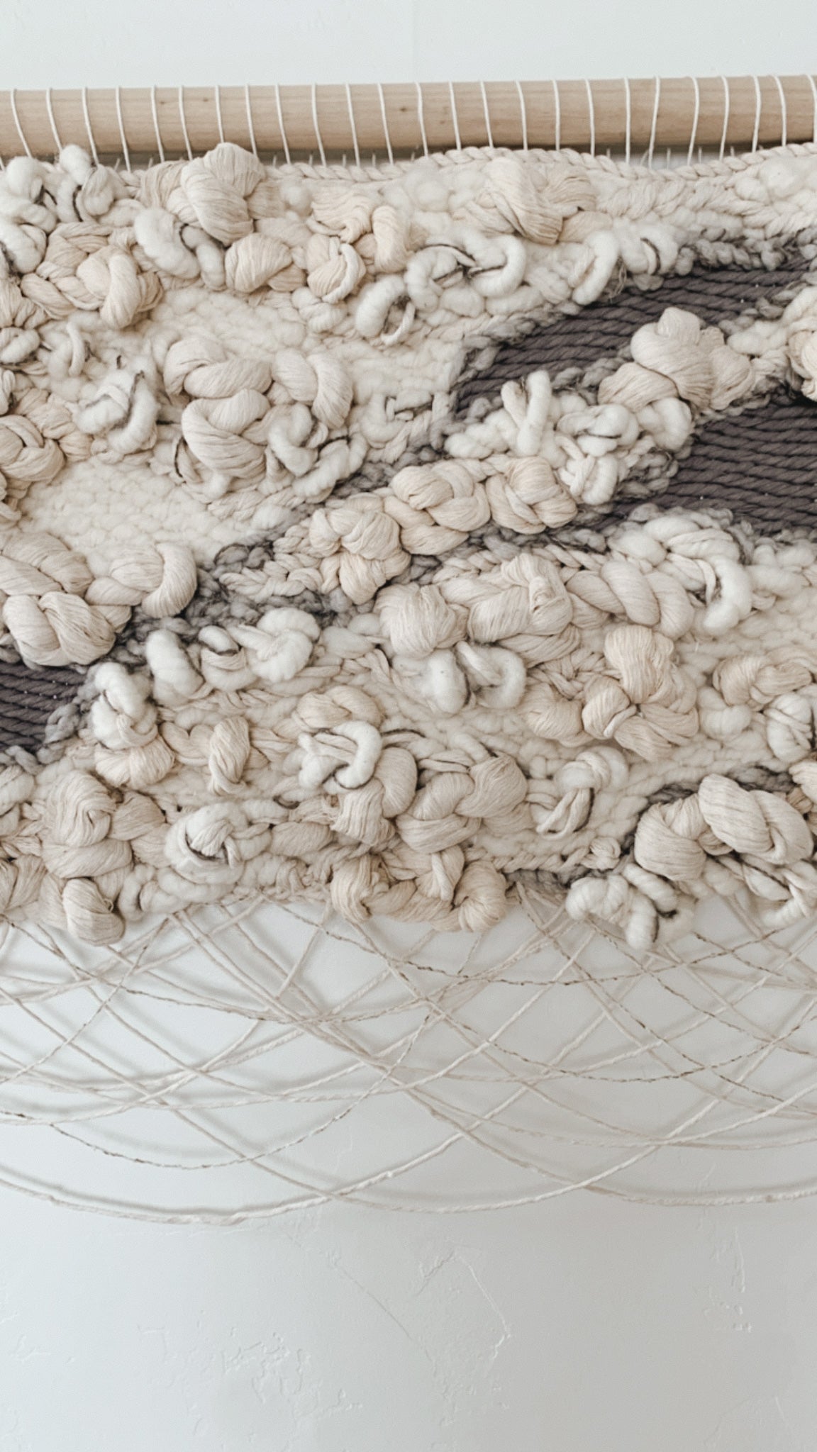 Organic fiber wall art piece utilizing natural wool and cotton, exuding warmth and tactile appeal. Tones of beige, ivory, buff, and gray.