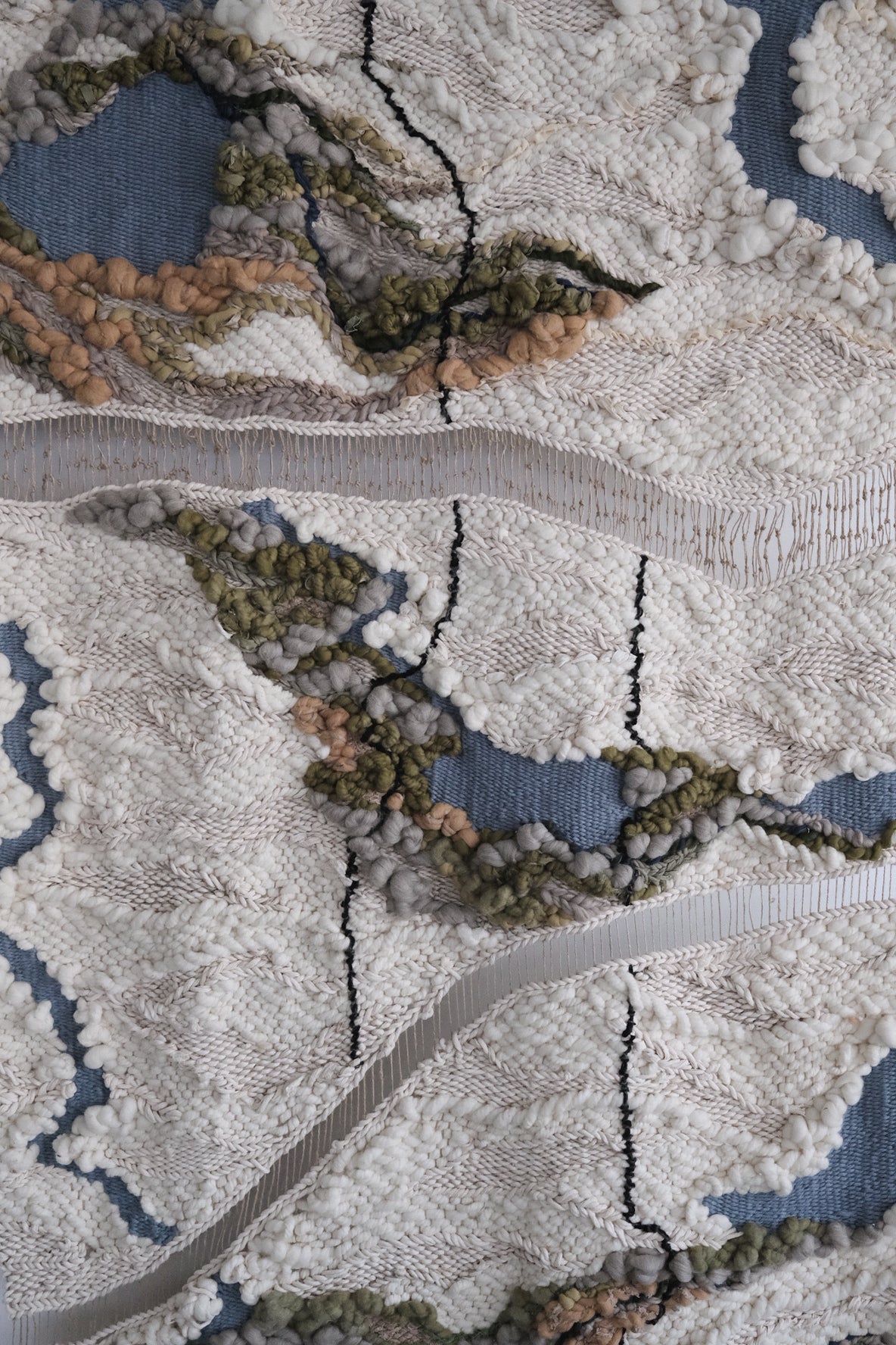 Handwoven wall hanging in natural fibers, combining wool, cotton, and textured yarns. Modern textile art with organic shapes and layered weaving techniques.