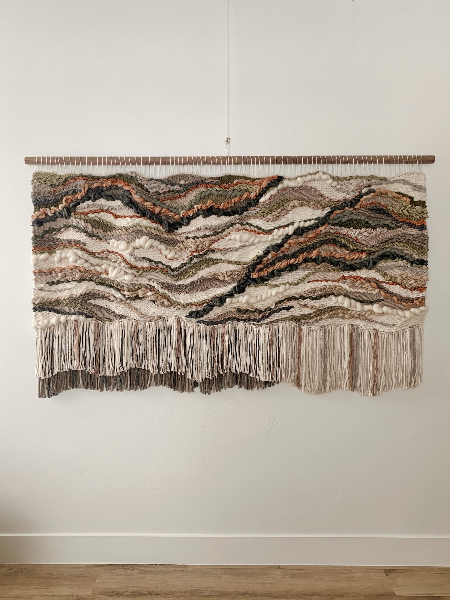 Soft fiber installation in muted tones, highlighting layered weaves and handcrafted movement.