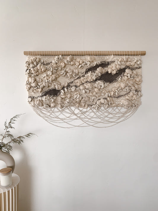 Organic fiber wall art piece utilizing natural wool and cotton, exuding warmth and tactile appeal.