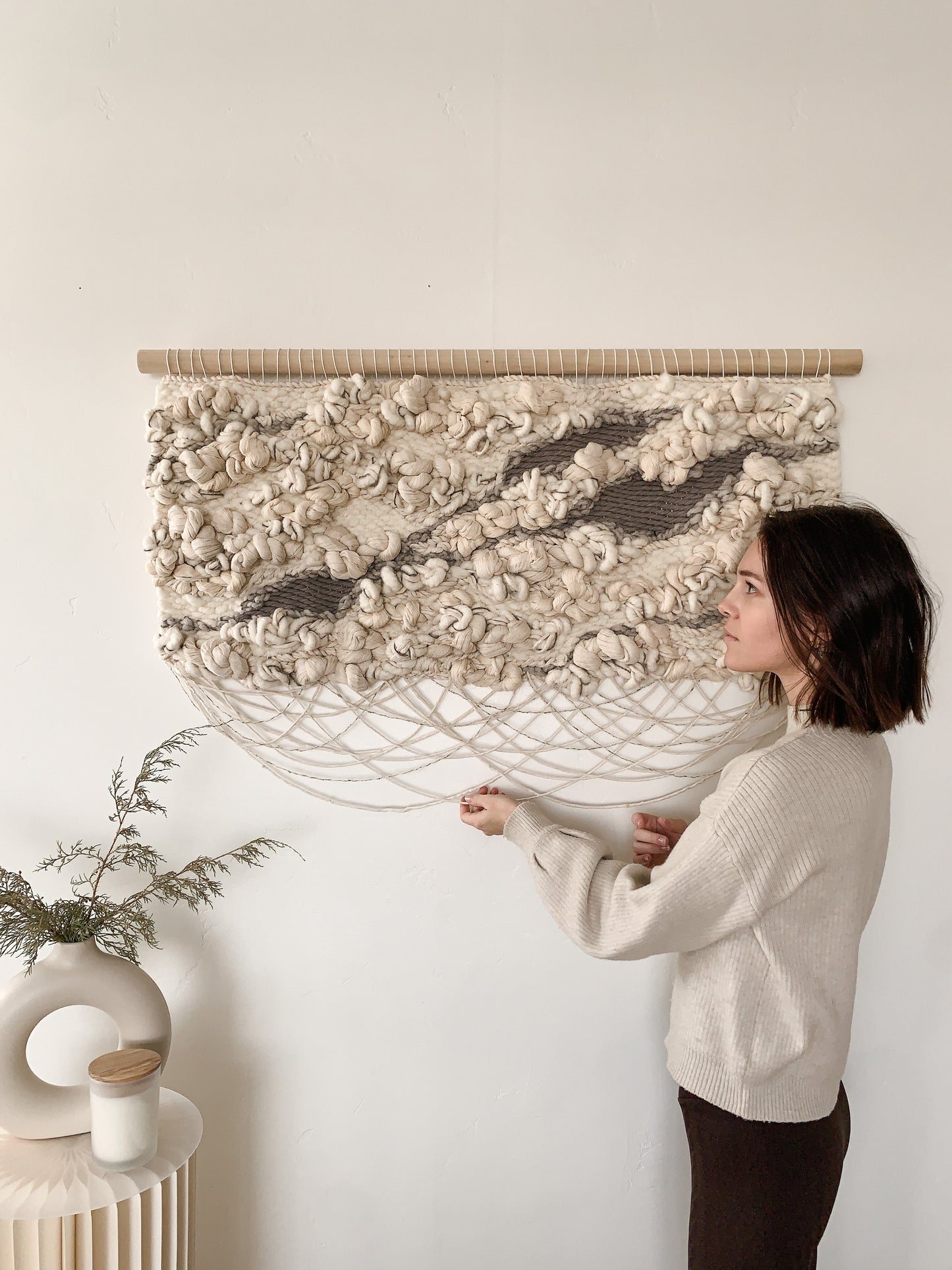 Organic fiber wall art piece utilizing natural wool and cotton, exuding warmth and tactile appeal. Knotted textures with crossing fringe.