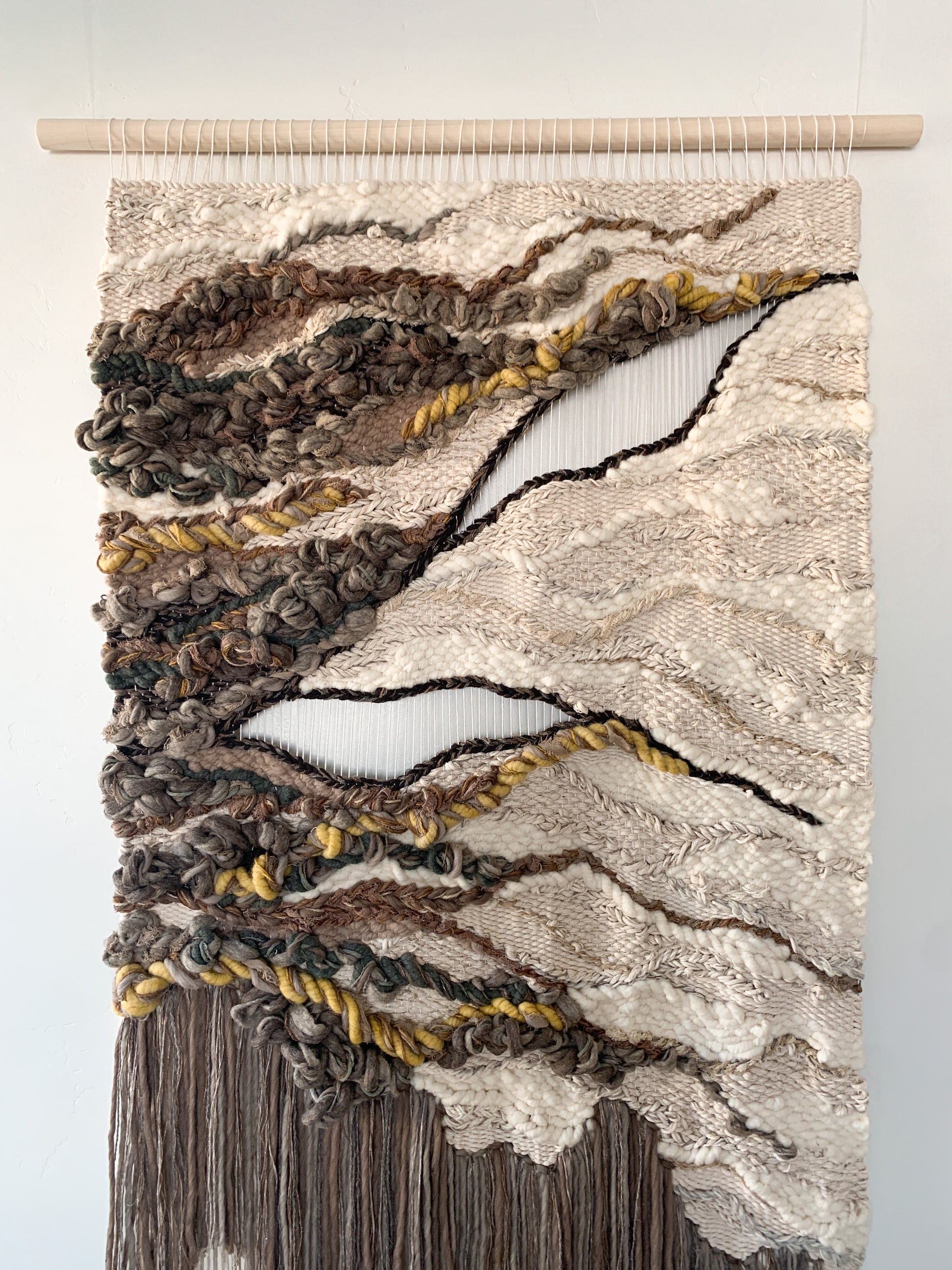 Wool and cotton art piece woven into an abstract landscape-inspired design with rich tactile contrast.
Negative space with open threads. Knotted and twisting yarn.