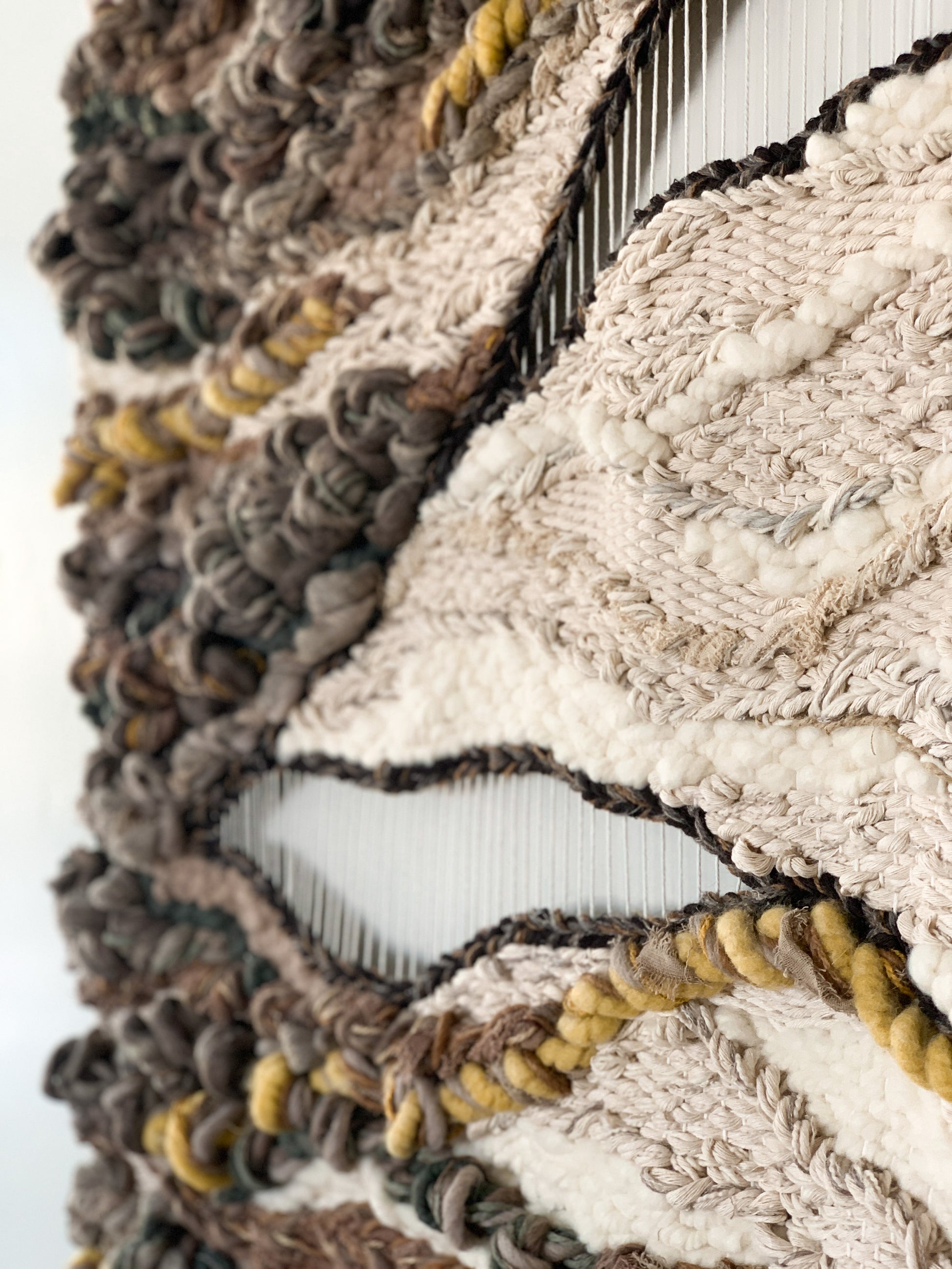 Wool and cotton art piece woven into an abstract landscape-inspired design with rich tactile contrast.
Negative space with accent colors in ochre, burnt orange, greens, beige, ivory, and brown.