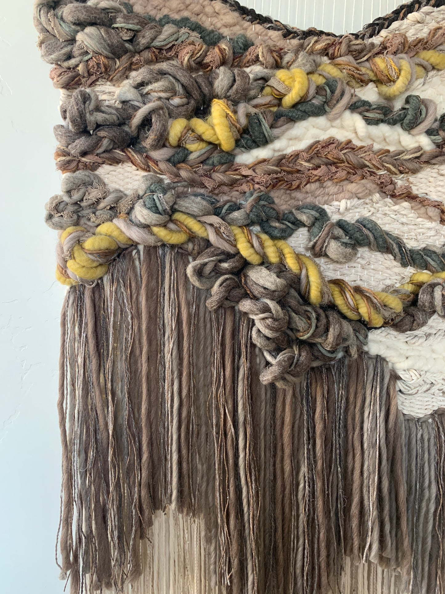 Wool and cotton art piece woven into an abstract landscape-inspired design with rich tactile contrast.
 Accent colors in browns, grays, beige tones, yellow, muted green and burnt orange.