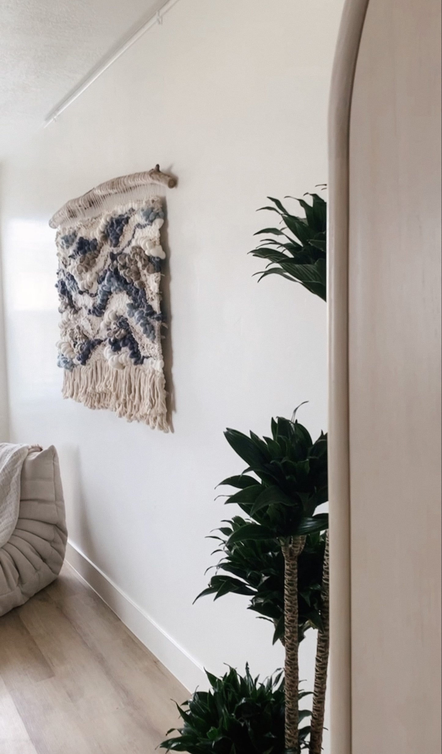 Architectural fiber art installation combining earthy threads and bold topographic motifs.
 Accent color in blue, gray, brown and tones of beige.