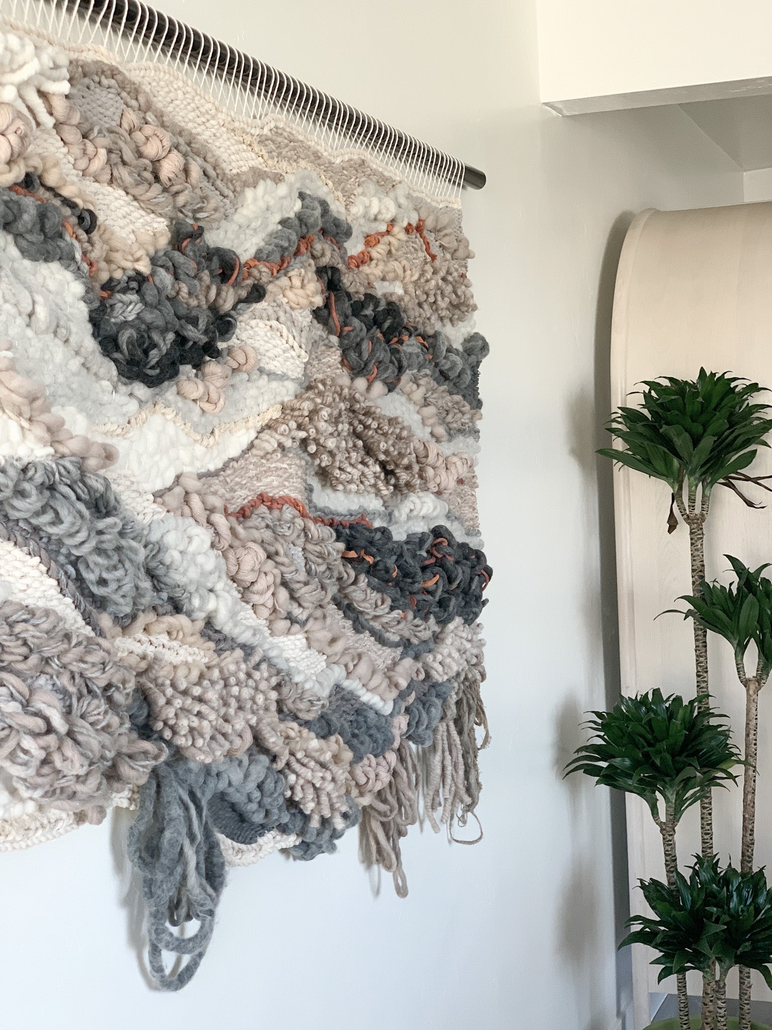 Wool and cotton art piece woven into an abstract landscape-inspired design with rich tactile contrast. Knotted and looped texture of face and fringe.