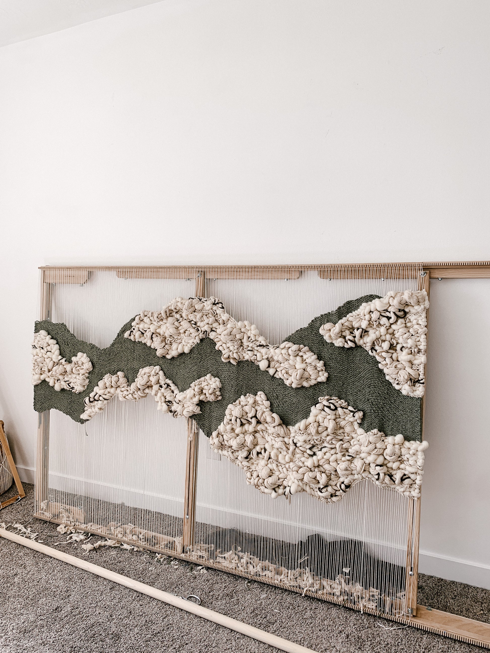 Tactile wall artwork made from plant-based fibers, reflecting a grounded and elemental visual story. Woven green mat face with accent bubbly knotted texture.