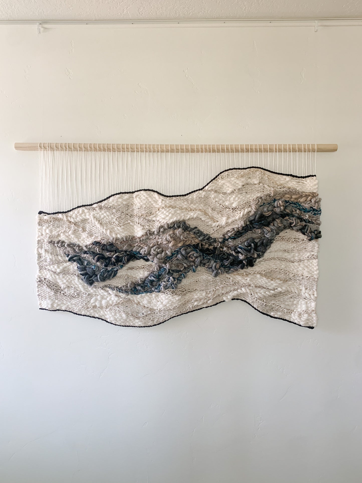 Handwoven fiber art wall hanging featuring intricate textures and organic patterns in natural tones.