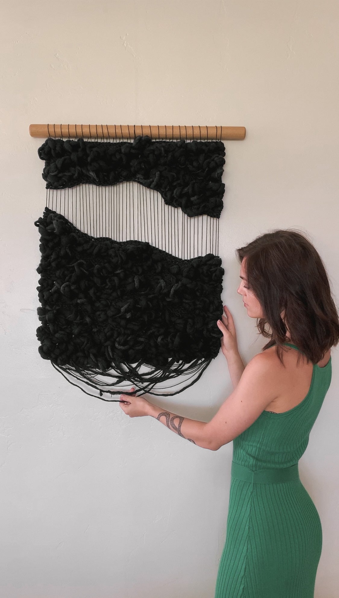 Abstract fiber art tapestry incorporating upcycled materials, reflecting a commitment to sustainable artistry. Negative space with knotted face.