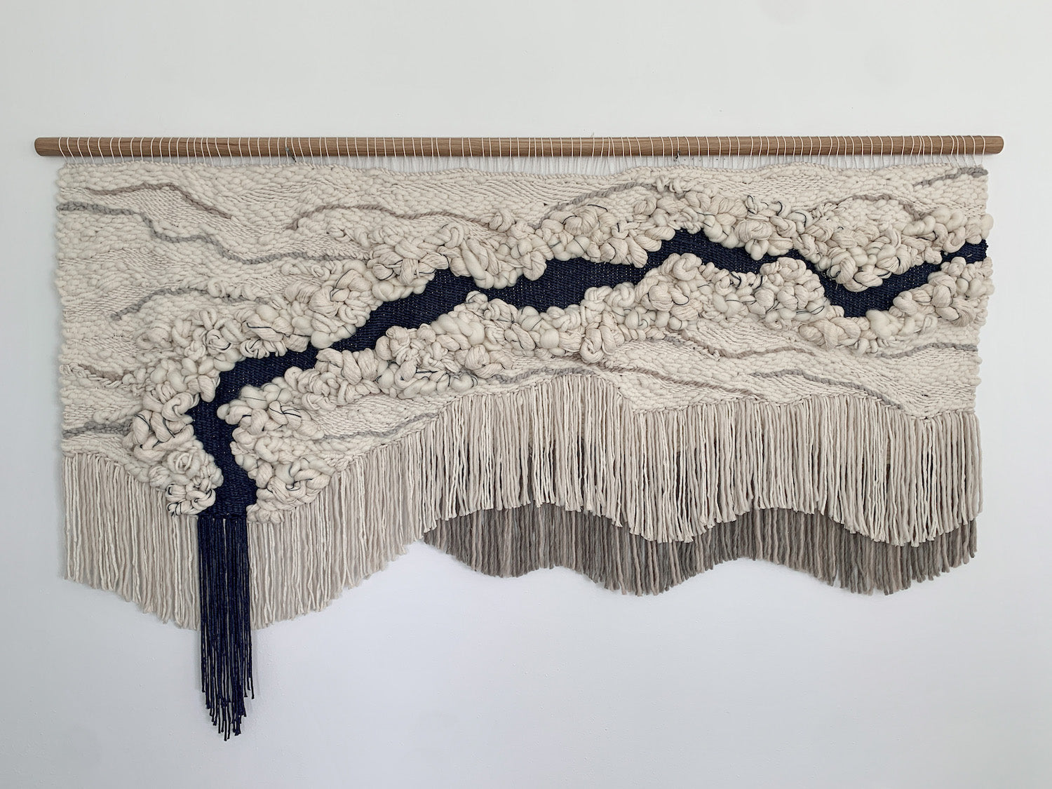 Minimalist fiber art tapestry with clean lines and neutral tones, perfect for serene and modern spaces. Accent color in beige tones, gray, and blue.