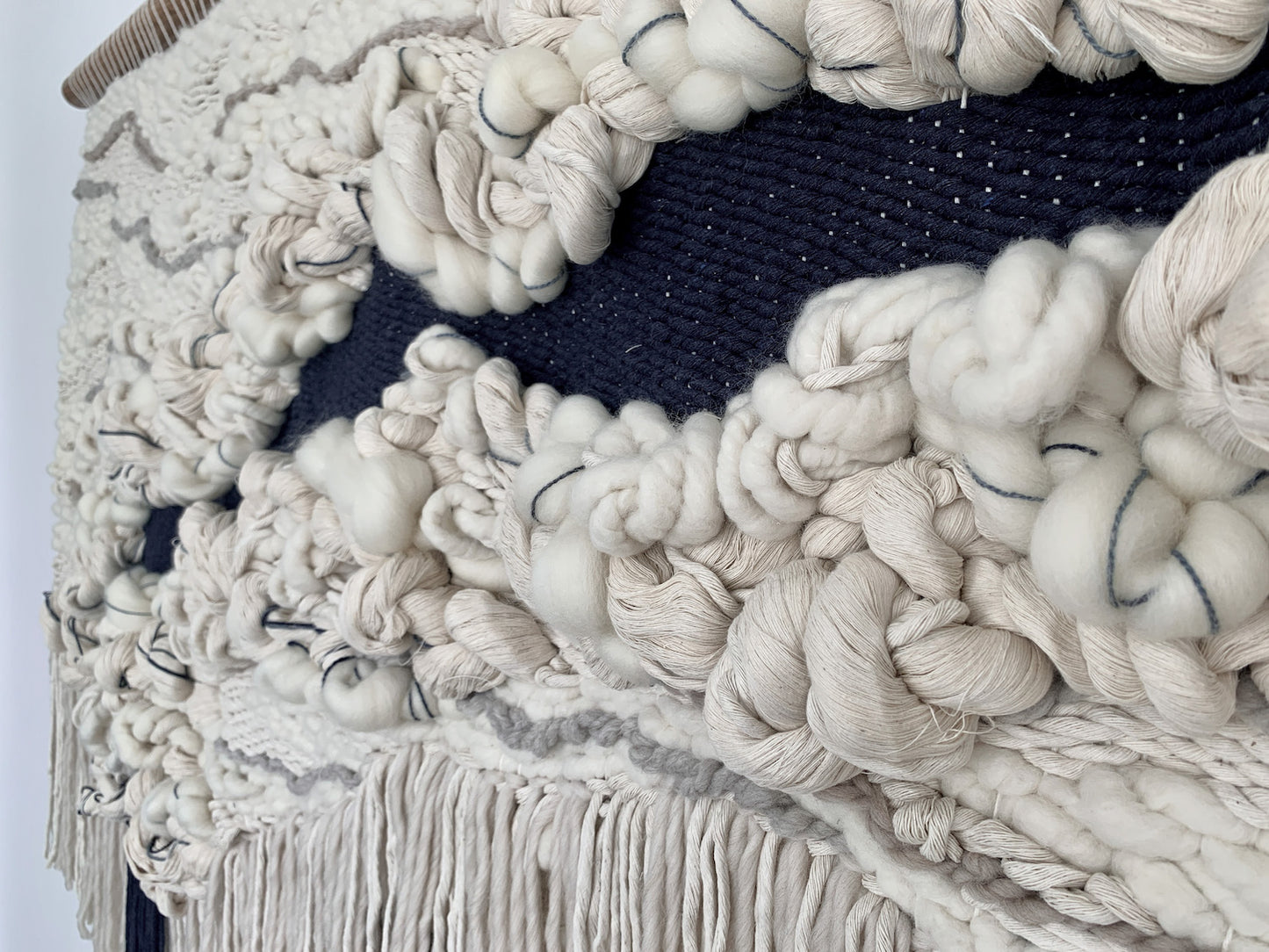 Minimalist fiber art tapestry with clean lines and neutral tones, perfect for serene and modern spaces. Heavy knotted textures with organic shape.