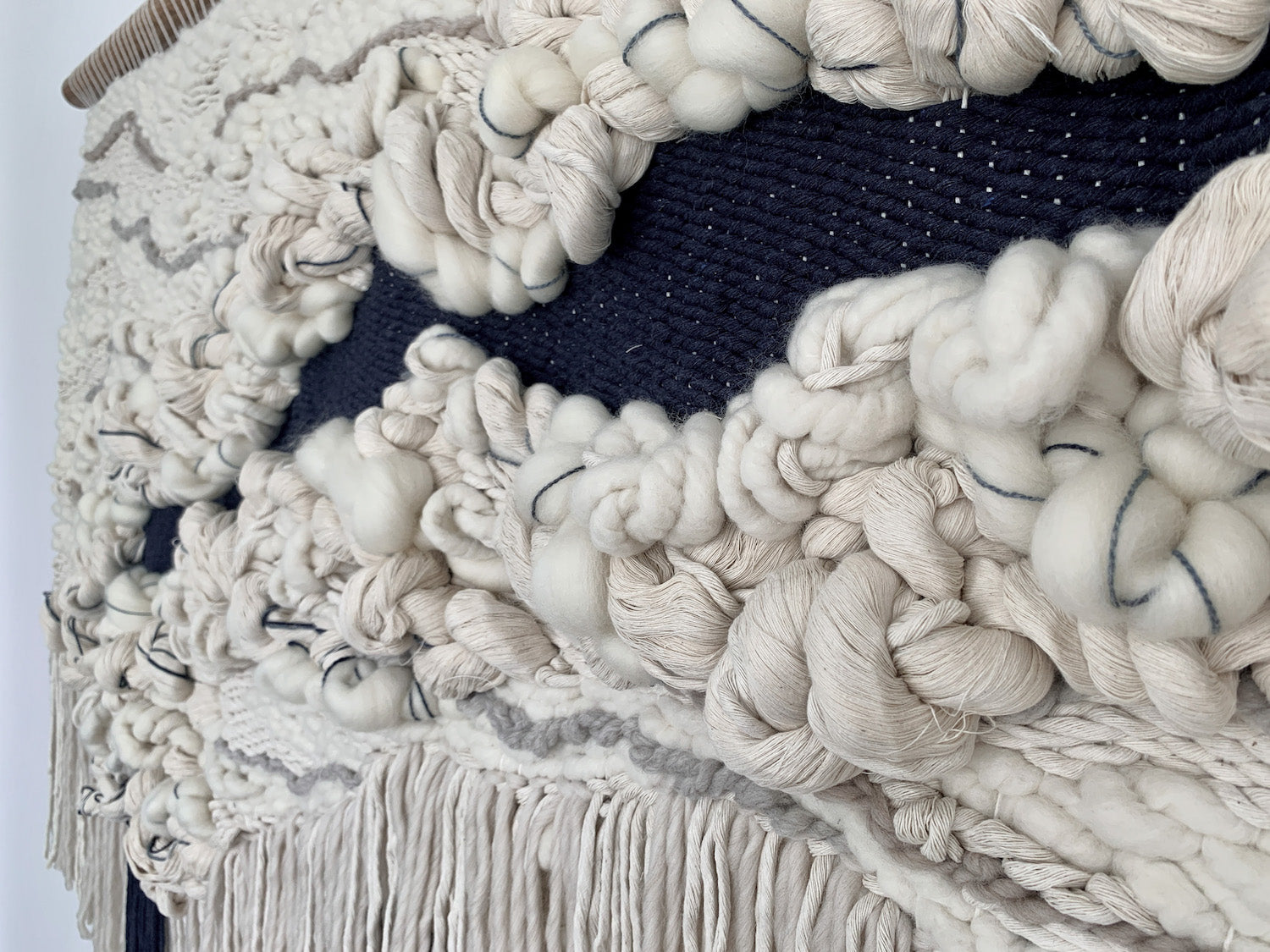 Minimalist fiber art tapestry with clean lines and neutral tones, perfect for serene and modern spaces. Heavy knotted textures with organic shape.