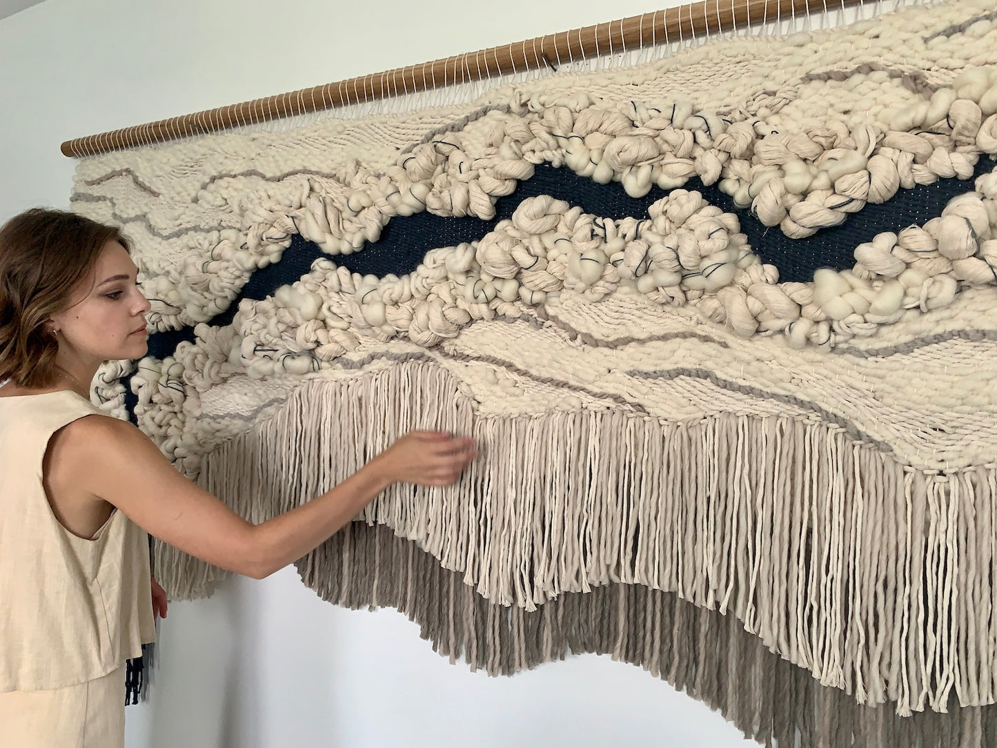 Minimalist fiber art tapestry with clean lines and neutral tones, perfect for serene and modern spaces. Accent colors in beige tones with blue and brown gray.