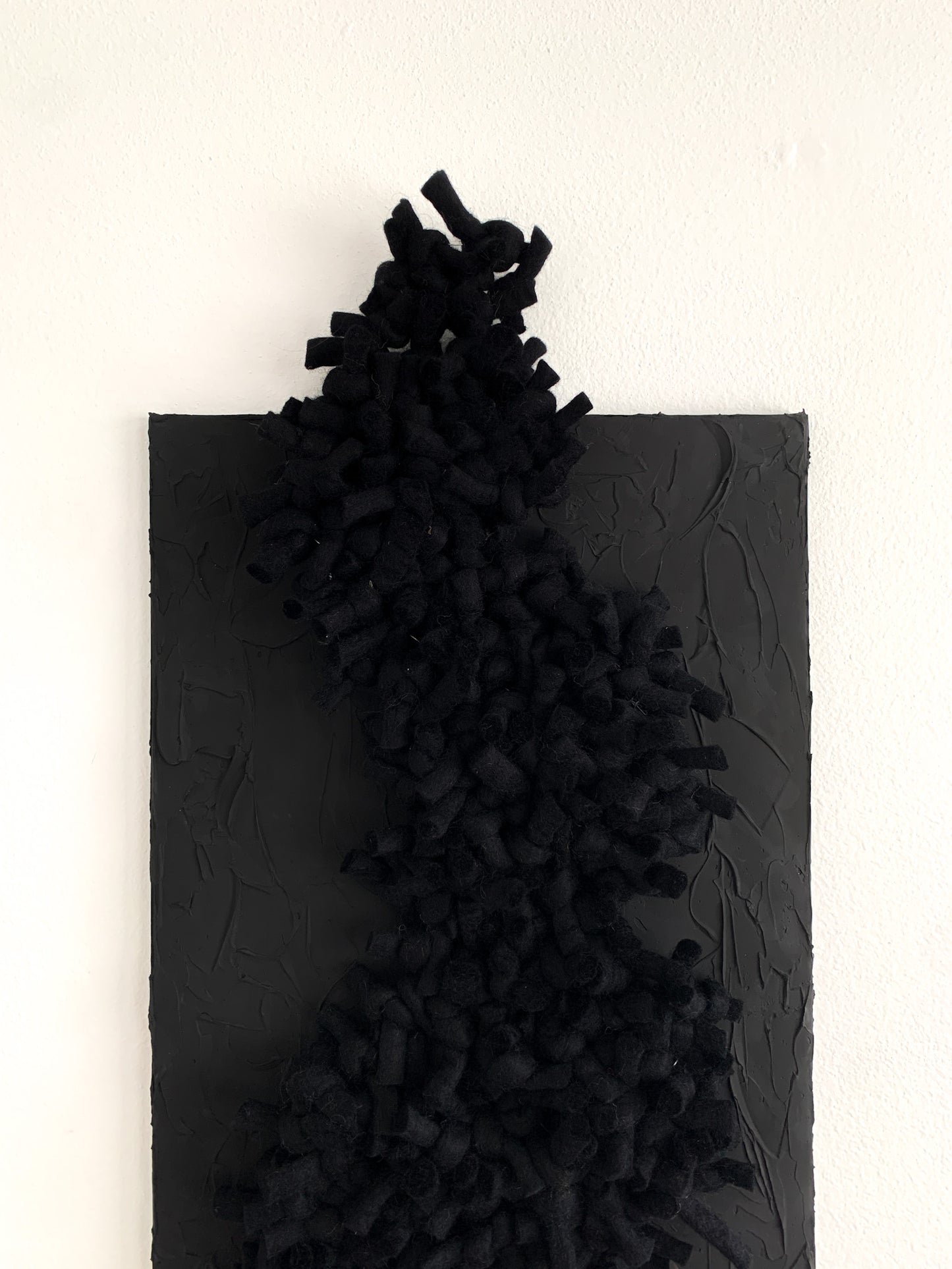 Handwoven black abstract wall piece with rich, tonal textures and dimensional fiberwork, blending wool and cotton in an intimate, sculptural composition.