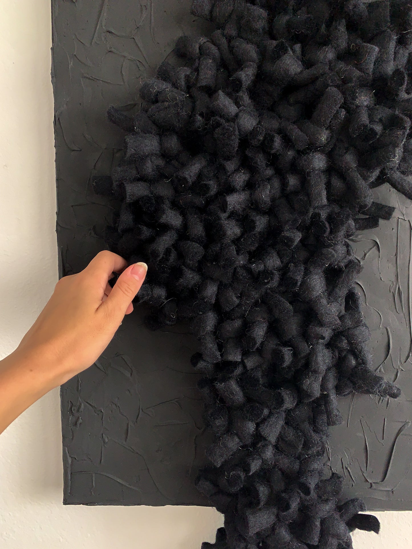 Handwoven black abstract wall piece with rich, tonal textures and dimensional fiberwork, blending wool and cotton in an intimate, sculptural composition.