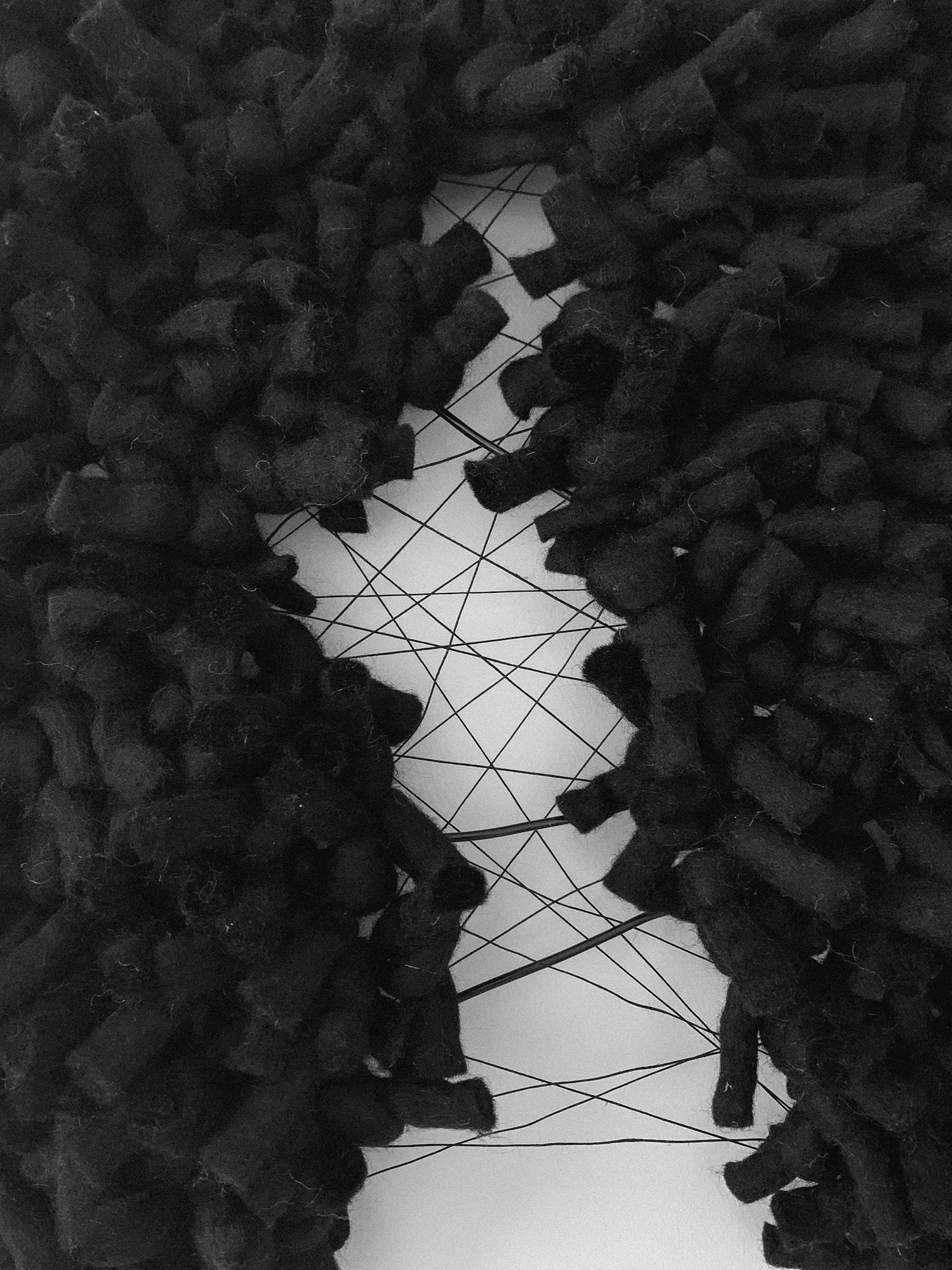 Handcrafted wall hanging with intricate interknot techniques, creating depth and movement in the design. Organic shape and flow with tear and supporting threads. Accent color in black.