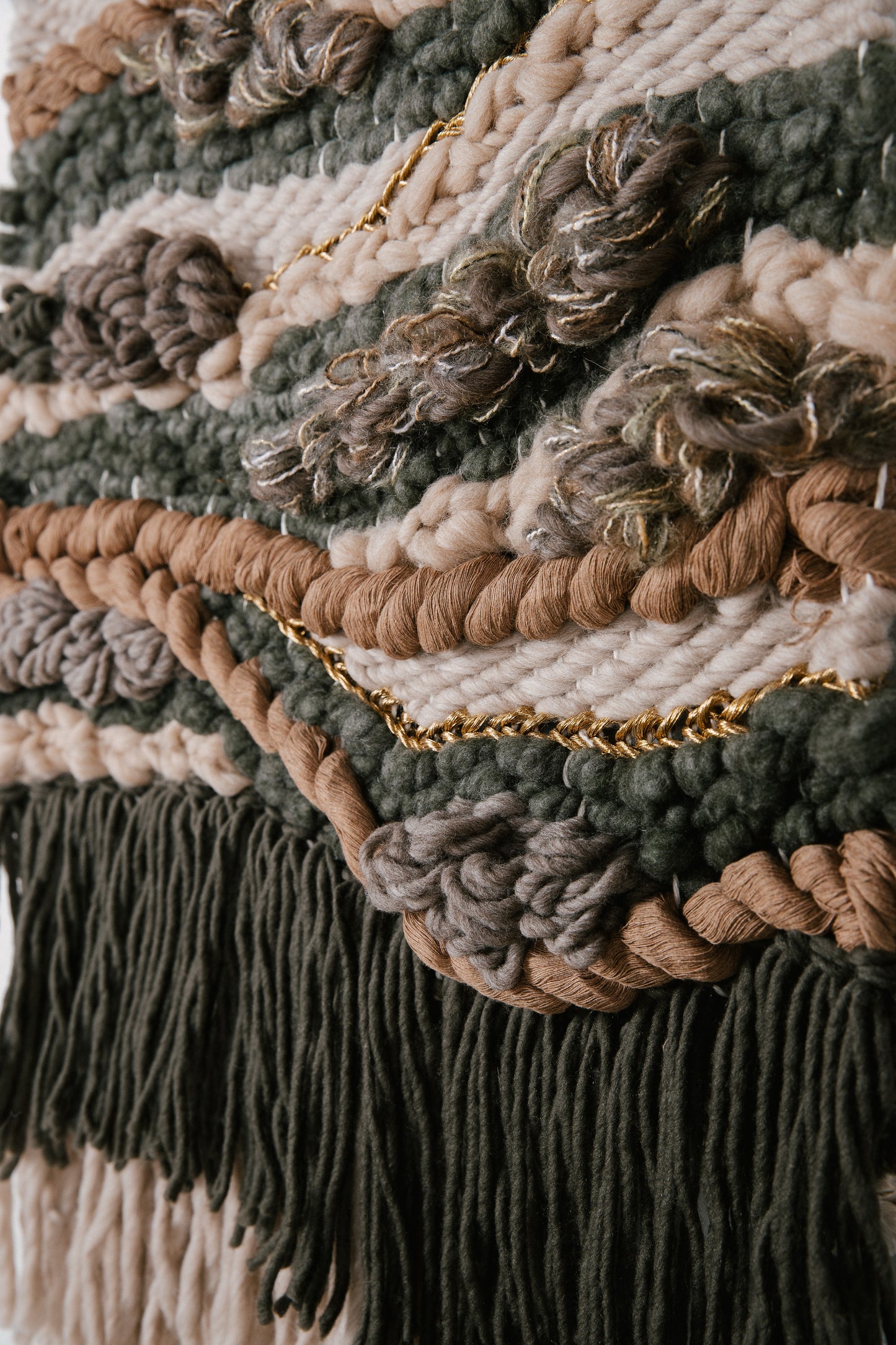 Organic fiber wall art piece utilizing natural wool and cotton, exuding warmth and tactile appeal. Accent colors in green, camel, gold, ivory, buff, beige, and more earthy tones.